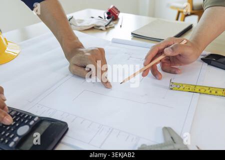 Architect man holding pencil working with blueprints for architectural plan Stock Photo