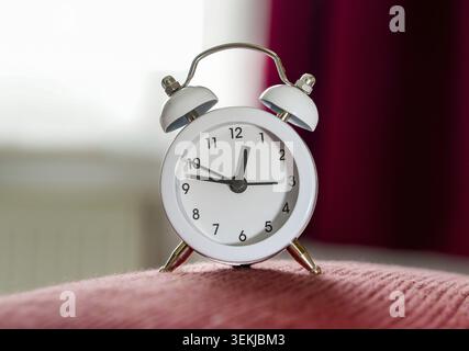 Analog mini bell alarm clock in white with a classic retro design. Compact travel alarm clock or decorative bedside clock Stock Photo