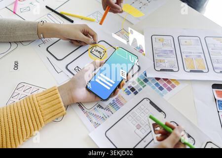 Process of creating an interface for a mobile app. User interface and experience concept. Modern app on smart phone in woman hands Stock Photo