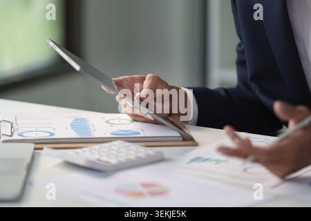A business professional analyzes charts and graphs on a tablet, emphasizing data-driven decision-making in the corporate environment Stock Photo