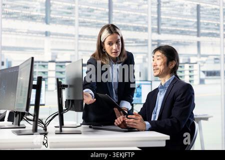 Female hardware designer and colleague optimize PCB production in microchip research office. SOC systems architects in circuit boards industry plant develop semiconductors powering electronics Stock Photo