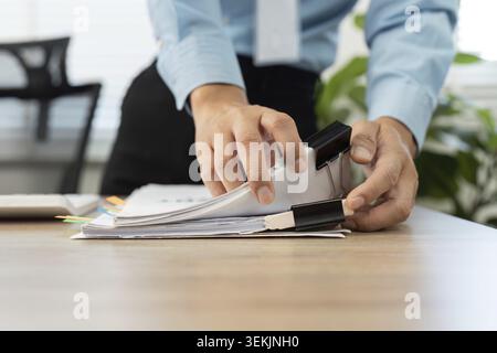 A businessman carefully organizing documents with binder clips, ensuring efficient management of paperwork in a professional setting Stock Photo
