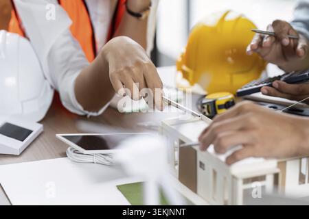 A team of engineers and planners collaborating on sustainable construction projects, reviewing architectural models and blueprints Stock Photo