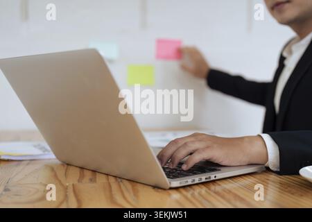 Businessperson working on laptop and typing on keyboard at table in office Stock Photo