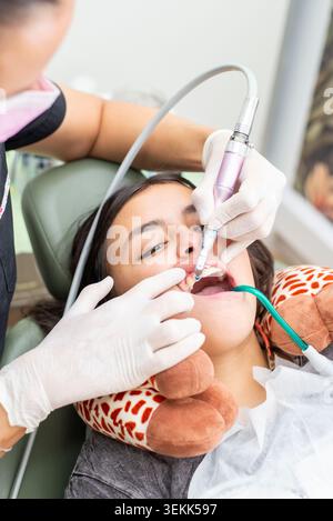 Dentist performing teeth cleaning on young patient teeth Stock Photo