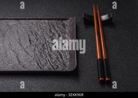 An empty ceramic square black plate with chopsticks for Asian food. An empty square plate as a food background for your design Stock Photo
