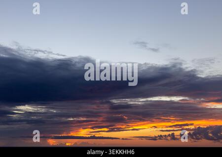 view of the sun rising behind the dark clouds over the ocean in summer Stock Photo