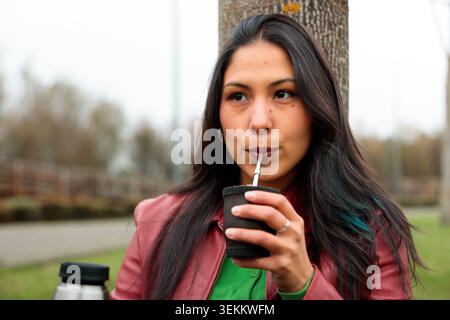 Close up of young Latina woman drinking traditional yerba mate outdoors in a park Stock Photo