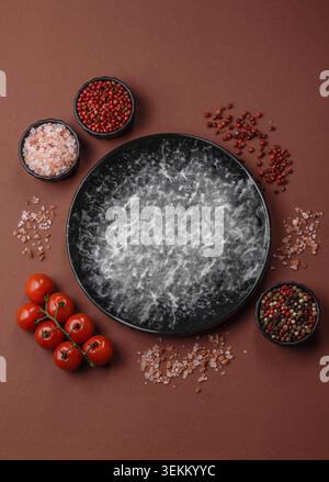 Empty round black plate for food, kitchen utensils on dining table. Empty plate on dark background Stock Photo