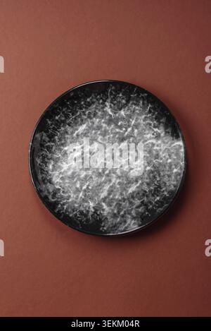 Empty round black plate for food, kitchen utensils on dining table. Empty plate on dark background Stock Photo