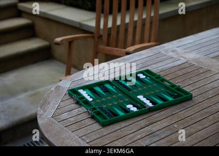 Green backgammon board set up on a wooden garden table for an outdoor game in a private patio setting. Stock Photo