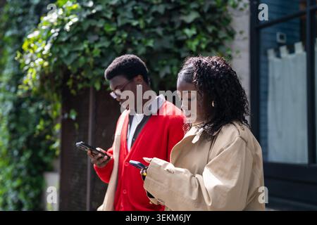 Focused african american man and woman students phone addicts scrolling online on smartphones Stock Photo
