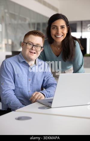 Portrait of man with Down syndrome working with colleague Stock Photo
