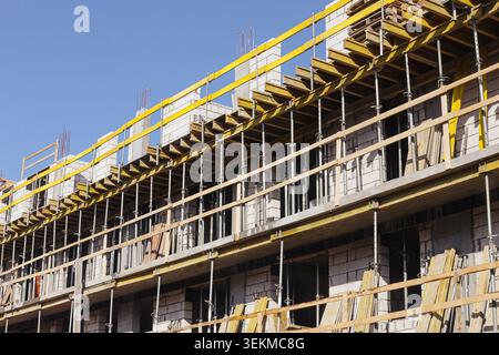 Commercial building under construction with scaffolding. Development project and construction industry concept outdoors. Stock Photo