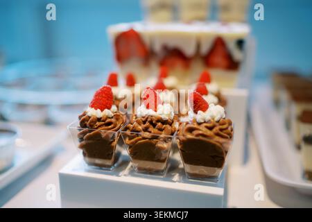 Chocolate dessert cups topped with strawberries on a buffet display Stock Photo