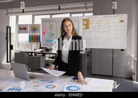 Businesswoman analyzing colorful pie charts and bar graphs in office Stock Photo