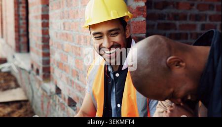 Laugh, men and construction workers in conversation on site for home renovation in collaboration. Happy, break and male civil engineers in discussion Stock Photo
