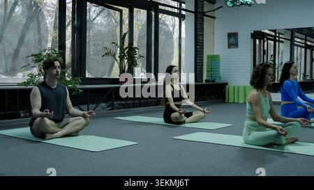 Group of mindful active people sitting down on the floor before starting wellnes Stock Photo