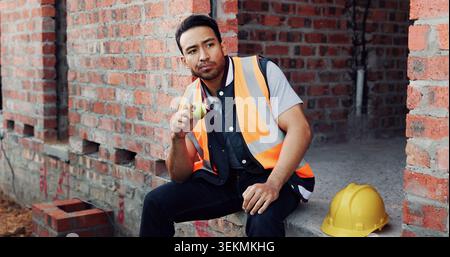 Man, architect or thinking with apple on lunch break or construction site for recovery, rest or meal. Thoughtful contractor, male person or civil Stock Photo