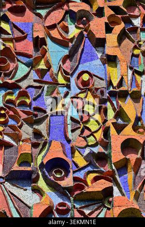 Colorful abstract relief mosaic wall art with carved geometric shapes, circles and triangles in warm earthy tones and blue accents. Textured pattern b Stock Photo