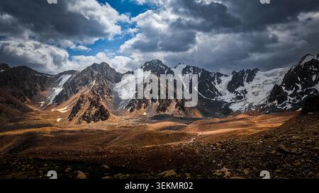 Dramatic Mountain Range with Tuyuk-Su Glacier and Stormy Clouds Stock Photo