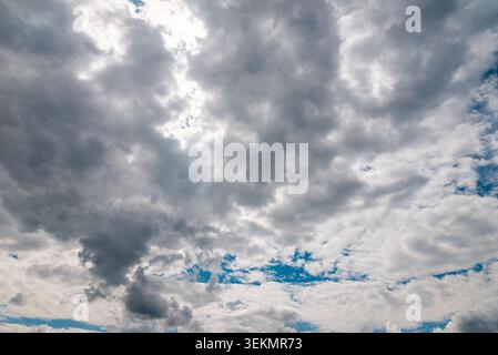 Dark storm clouds with sunlight breaking through dramatic sky background. Stock Photo