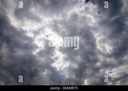 Dark storm clouds with sunlight breaking through dramatic sky background. Stock Photo