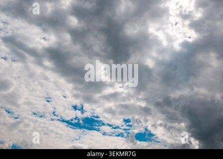 Dark storm clouds with sunlight breaking through dramatic sky background. Stock Photo
