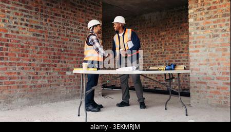 Shaking hands, men and construction workers on site with partnership, agreement or deal on building. Infrastructure, collaboration and male civil Stock Photo