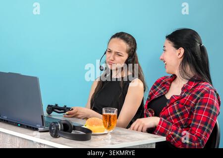 Two young women discussing creative project work using laptop at table Stock Photo
