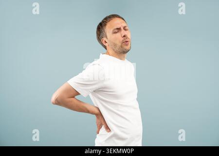 Unwell man holding lower back in pain with discomfort feels symptoms of backache, muscle strain, sciatica, herniated discs. Distressed middle-aged mal Stock Photo