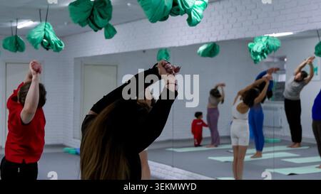 People attending group fitness class doing stretching exercises indoor Stock Photo