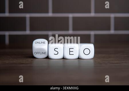 White blocks spelling SEO next to a turned cube showing ONLINE and OFFLINE text. Digital marketing adjustments, local search engine optimization Stock Photo