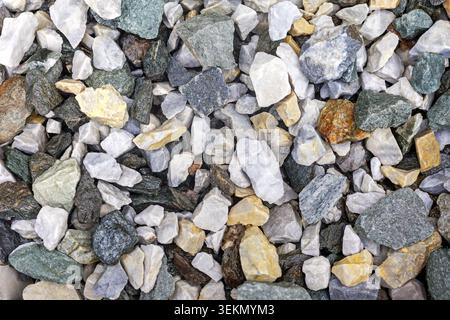 Mixed gravel stones texture background. Close-up view of assorted rough gravel stones in white, gray, green, and yellow tones for natural texture Stock Photo