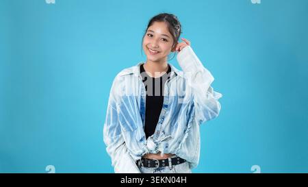 Smiling young asian woman touching her head with hand looking cheerful Stock Photo