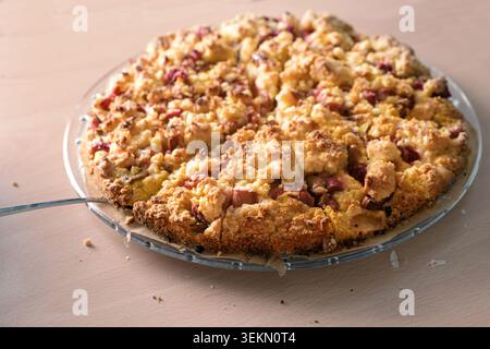 Rhubarb crumble cake on a glass plate and a wooden table, homemade dessert, baking for holiday casual holiday events like birthday or a gathering with Stock Photo