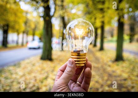 Hand of man holding illuminated light bulb at street Stock Photo