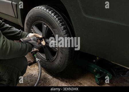 Mechanic using wrench while changing car tire in garage Stock Photo