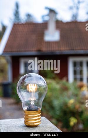 Glowing light bulb kept on outdoor table Stock Photo