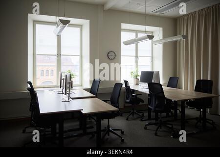 Empty desks with computers and chairs in tech office Stock Photo