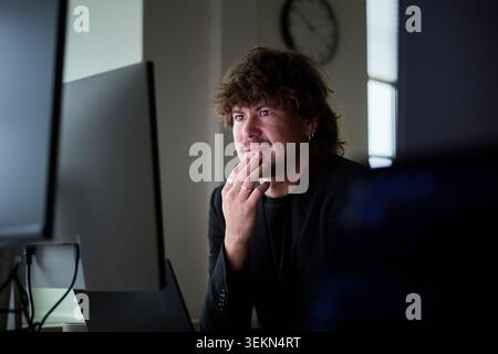 Thoughtful male business expert working on desktop PC in tech office Stock Photo