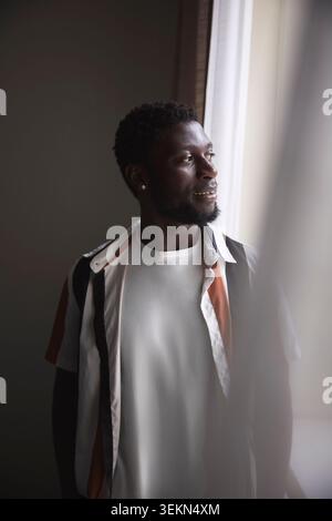Thoughtful businessman looking away while standing near window in office Stock Photo