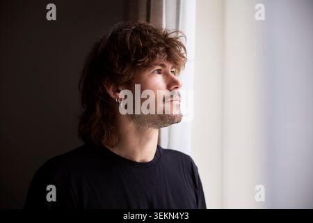 Contemplative male entrepreneur with long hair looking away Stock Photo