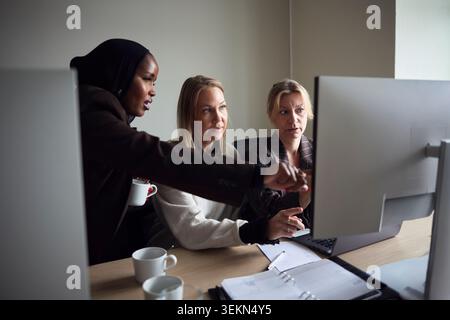 High angle view of multiracial female business professionals discussing ideas with each other on desktop PC in office Stock Photo
