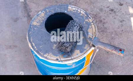 Paint Roller on Open Gray Paint Bucket Close Up Stock Photo