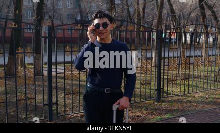Handsome stylish young man standing near metal fence holding Stock Photo