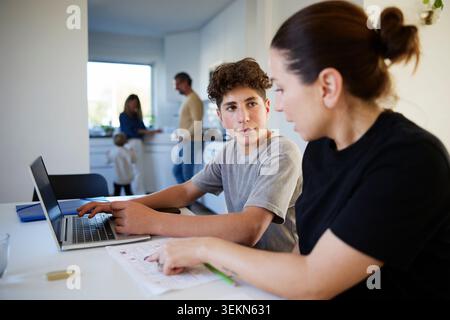 Boy listening to mother helping him while studying at home Stock Photo