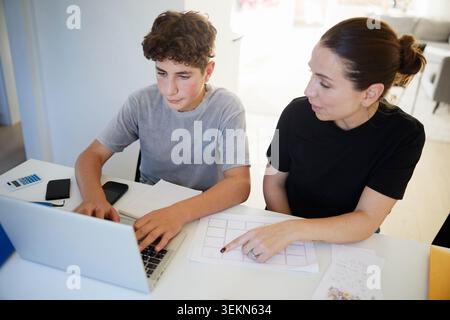 High angle view of mother assisting her son while studying at home Stock Photo