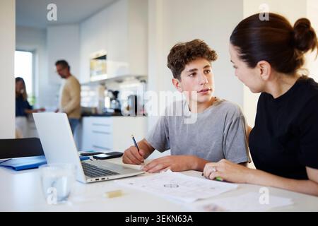 Boy taking guidance from his mother while studying at home Stock Photo