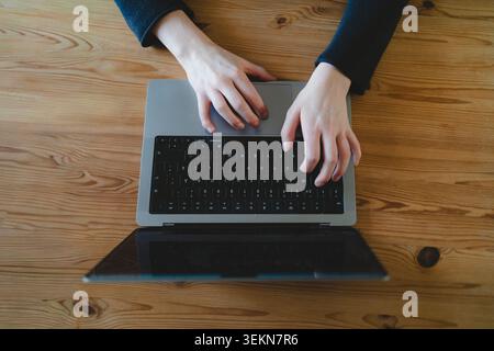 Directly above view of female freelance worker using laptop on wooden table Stock Photo
